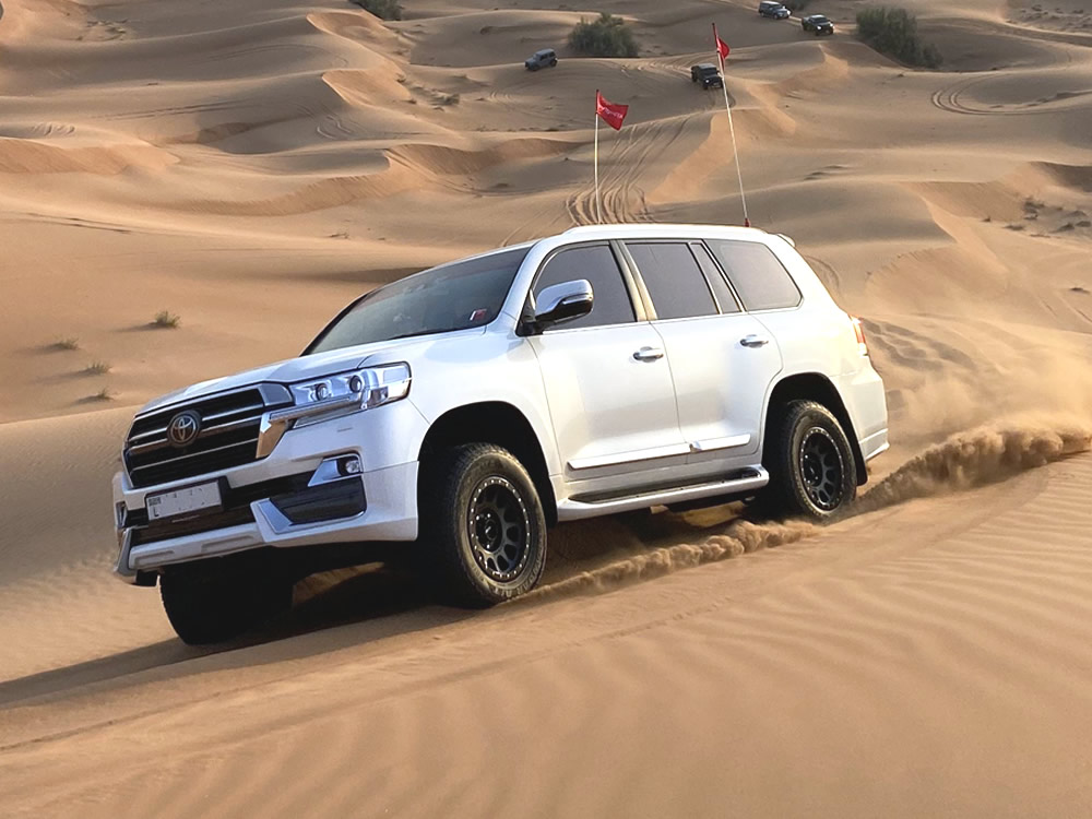 Private desert driving course in Dubai — student following marshal across sand dunes in stock 4x4